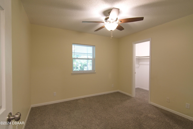 empty room featuring a textured ceiling, carpet flooring, and ceiling fan