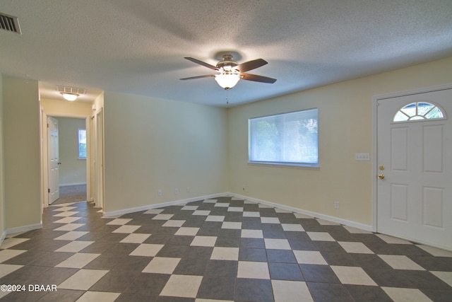 foyer entrance featuring a wealth of natural light, a textured ceiling, and ceiling fan