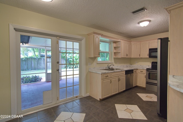 kitchen with a textured ceiling, appliances with stainless steel finishes, sink, and plenty of natural light