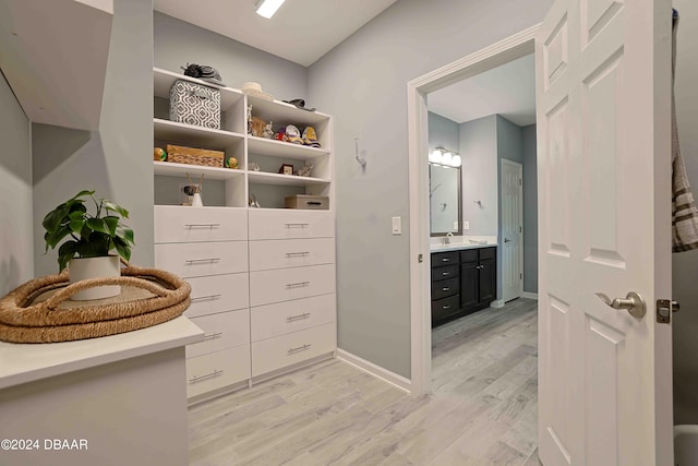 walk in closet with sink and light hardwood / wood-style flooring