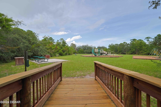 wooden deck with a playground and a yard