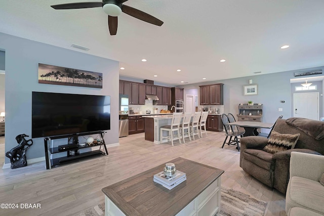 living room featuring ceiling fan and light hardwood / wood-style flooring