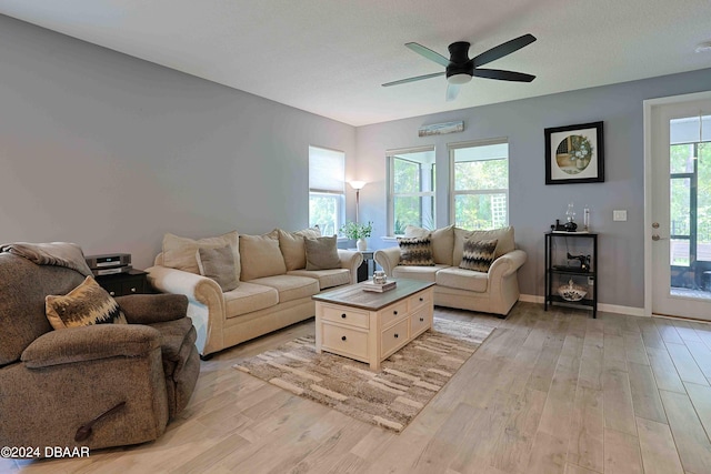 living room featuring ceiling fan, a textured ceiling, and light hardwood / wood-style flooring