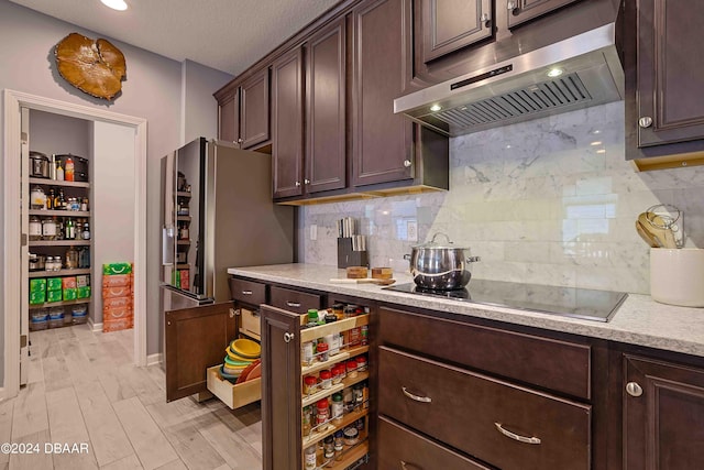 kitchen with black electric stovetop, decorative backsplash, dark brown cabinetry, a textured ceiling, and light wood-type flooring