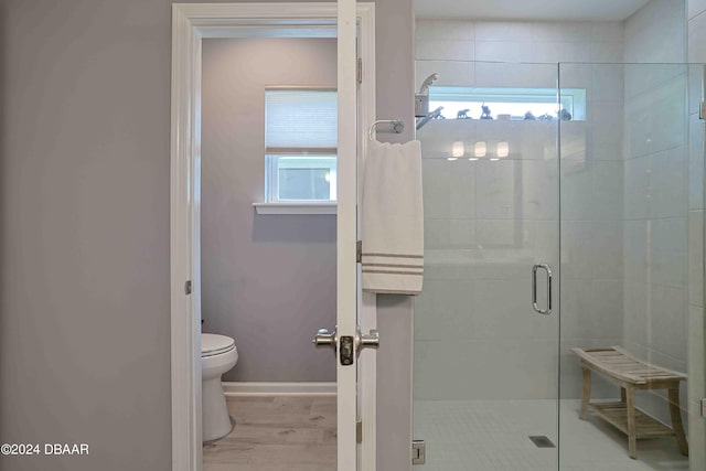 bathroom with hardwood / wood-style floors, toilet, and an enclosed shower