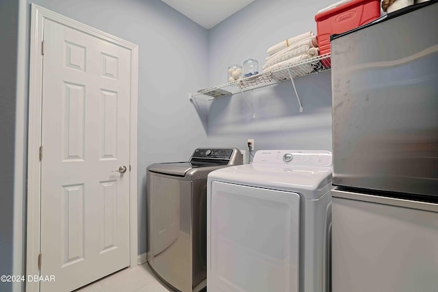 clothes washing area with separate washer and dryer and light tile patterned floors