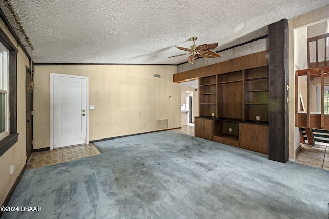 unfurnished living room with ornamental molding, a textured ceiling, light carpet, vaulted ceiling, and ceiling fan