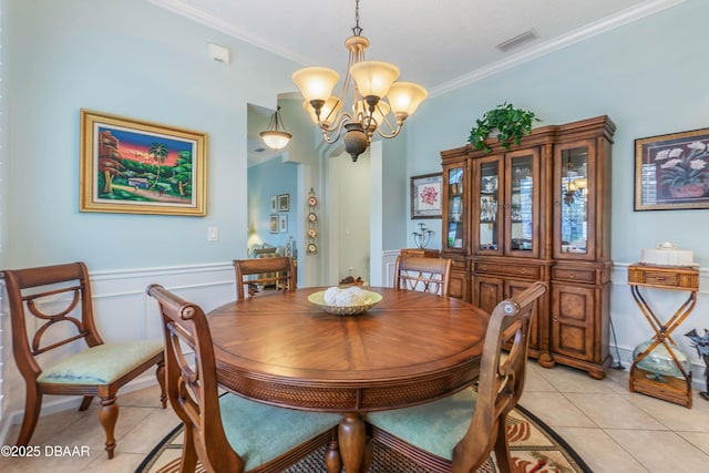 dining room with ornamental molding, light tile patterned flooring, and an inviting chandelier