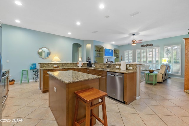 kitchen with built in shelves, a breakfast bar area, a center island, stainless steel dishwasher, and kitchen peninsula