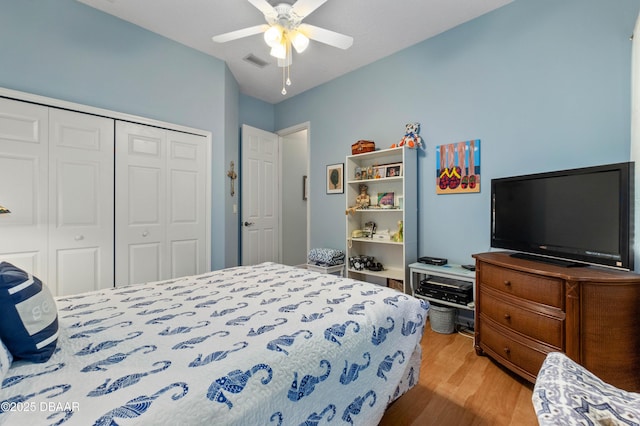 bedroom with light hardwood / wood-style flooring, ceiling fan, and a closet