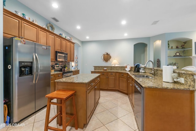 kitchen with sink, a breakfast bar area, built in features, a kitchen island, and stainless steel appliances