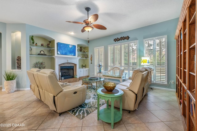 living room with light tile patterned floors, a fireplace, a textured ceiling, and built in shelves