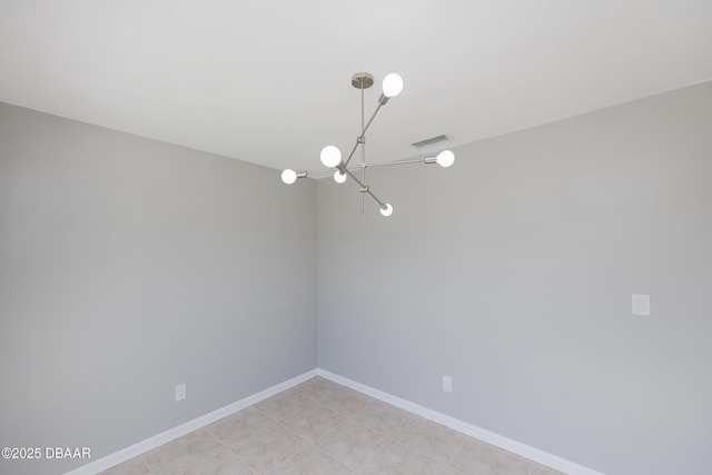 tiled spare room featuring a chandelier