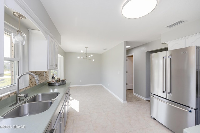 kitchen with sink, an inviting chandelier, white cabinetry, and high end fridge