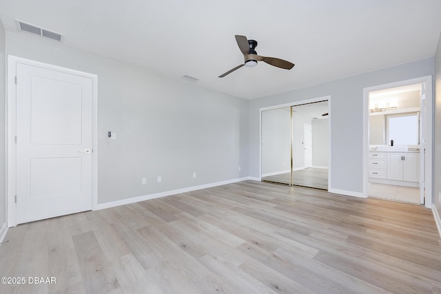 unfurnished bedroom featuring ceiling fan, ensuite bath, and light wood-type flooring