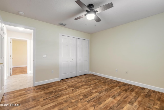 unfurnished bedroom featuring ceiling fan, a closet, and hardwood / wood-style floors