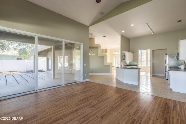 kitchen with kitchen peninsula, a chandelier, light wood-type flooring, white cabinets, and appliances with stainless steel finishes