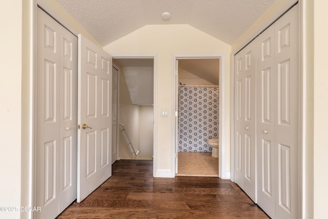 hallway featuring a textured ceiling, lofted ceiling, and dark hardwood / wood-style floors