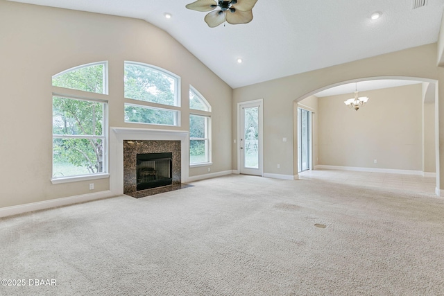 unfurnished living room with a premium fireplace, vaulted ceiling, light carpet, and ceiling fan with notable chandelier