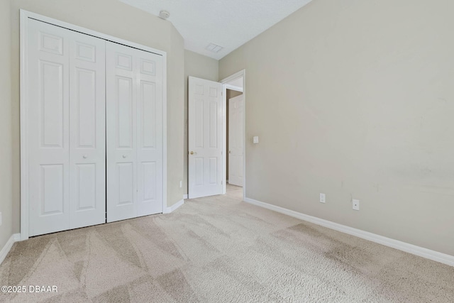 unfurnished bedroom featuring light colored carpet and a closet