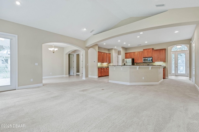 unfurnished living room with a wealth of natural light, an inviting chandelier, and light carpet