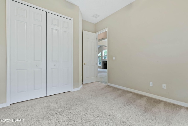 unfurnished bedroom with a closet, light carpet, and a fireplace