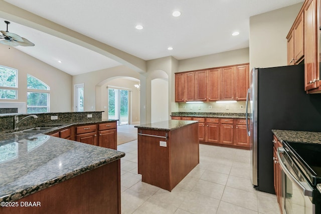 kitchen with dark stone counters, ceiling fan, a center island, and sink