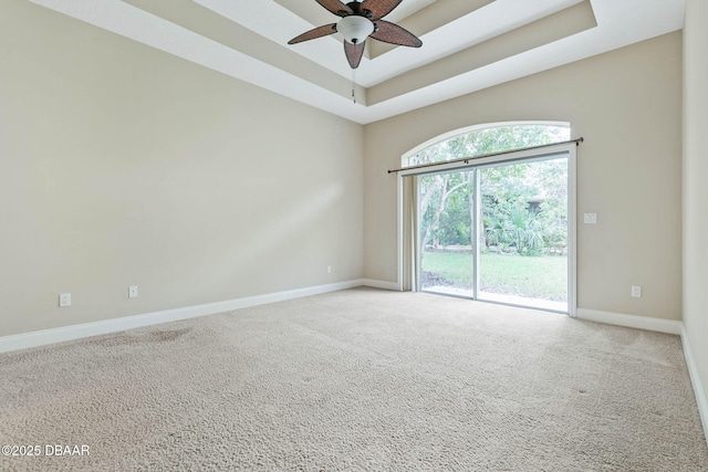 carpeted empty room featuring a raised ceiling and ceiling fan