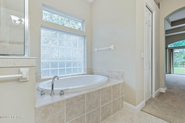 bathroom featuring tiled bath, tile patterned floors, and a healthy amount of sunlight