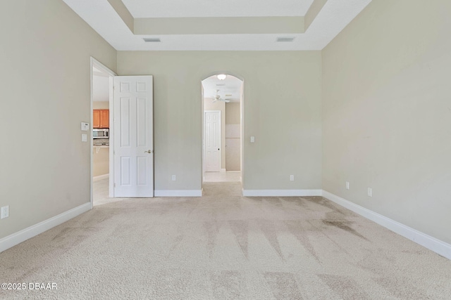 carpeted empty room with a raised ceiling