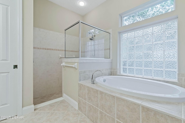 bathroom with a textured ceiling, separate shower and tub, and tile patterned floors