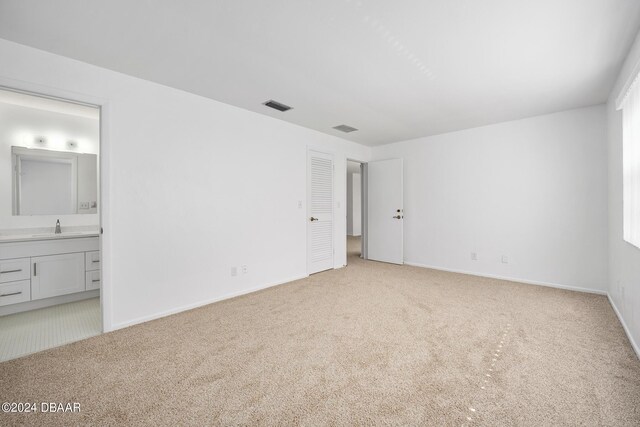 36 Dresden Cir, Ormond Beach, FL 32174 - unfurnished bedroom featuring light colored carpet, a sink, ensuite bath, and baseboards