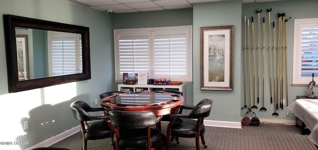 carpeted dining room with baseboards and a drop ceiling