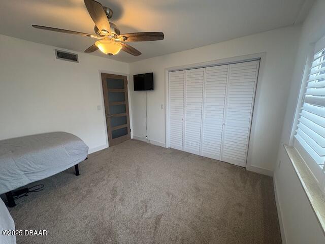 unfurnished bedroom with a closet, carpet floors, ceiling fan, and baseboards