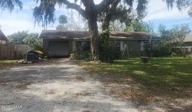 view of front facade with fence, concrete driveway, a front lawn, and a garage