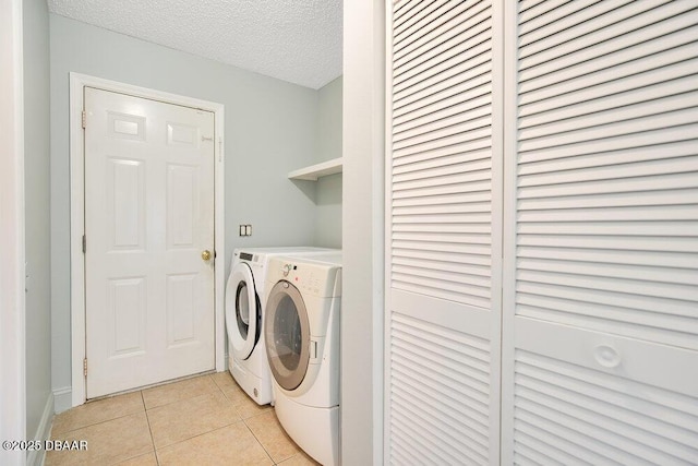 laundry room featuring light tile patterned flooring, washing machine and dryer, and a textured ceiling