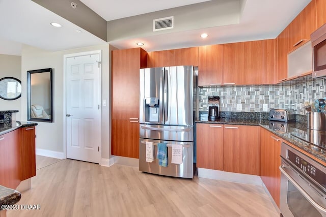 241 Riverside Dr Unit 410, Holly Hill, FL 32117 - kitchen with stainless steel appliances, brown cabinets, modern cabinets, light wood-style floors, and dark stone counters