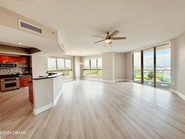 241 Riverside Dr Unit 410, Holly Hill, FL 32117 - unfurnished living room featuring a ceiling fan, baseboards, light wood-type flooring, a sink, and a textured ceiling