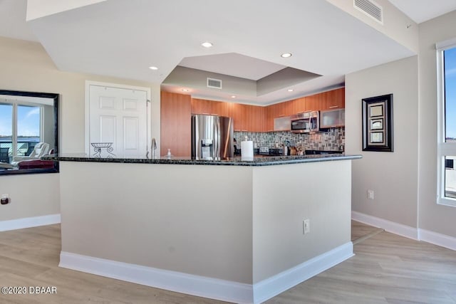 241 Riverside Dr Unit 410, Holly Hill, FL 32117 - kitchen with appliances with stainless steel finishes, brown cabinetry, dark stone counters, modern cabinets, and decorative backsplash