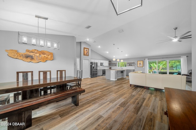 dining space with light hardwood / wood-style floors, ceiling fan, and vaulted ceiling