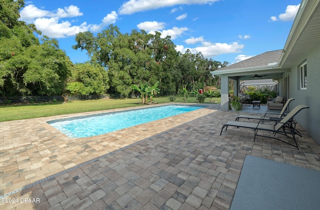 view of pool with ceiling fan, a patio, and a yard