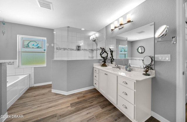 bathroom with independent shower and bath, wood-type flooring, vanity, and a textured ceiling