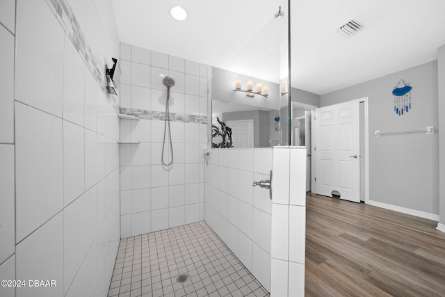 bathroom featuring hardwood / wood-style floors and tiled shower