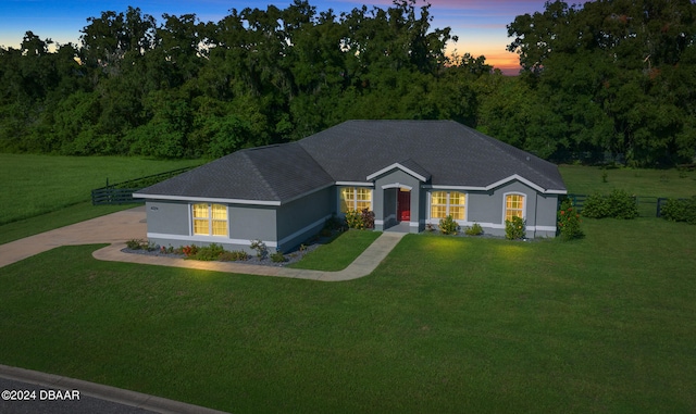 single story home featuring concrete driveway, a shingled roof, a front lawn, and fence