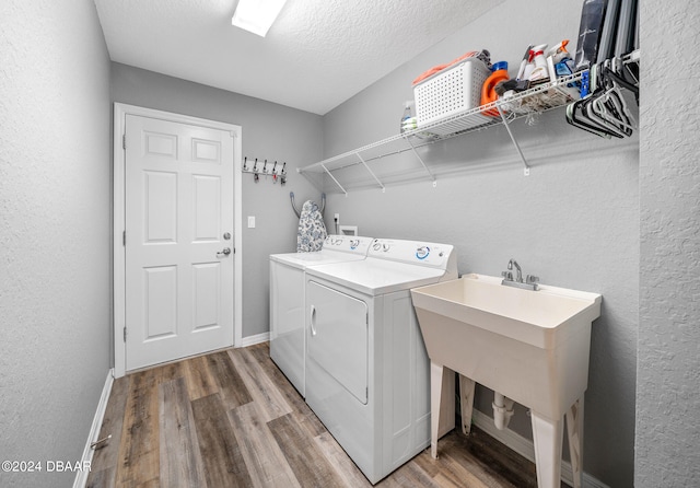 washroom featuring separate washer and dryer, wood-type flooring, a textured ceiling, and sink