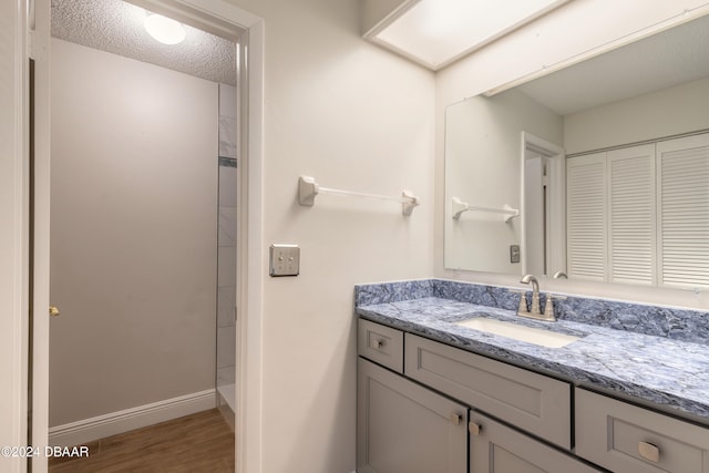 bathroom featuring hardwood / wood-style floors, vanity, a textured ceiling, and walk in shower