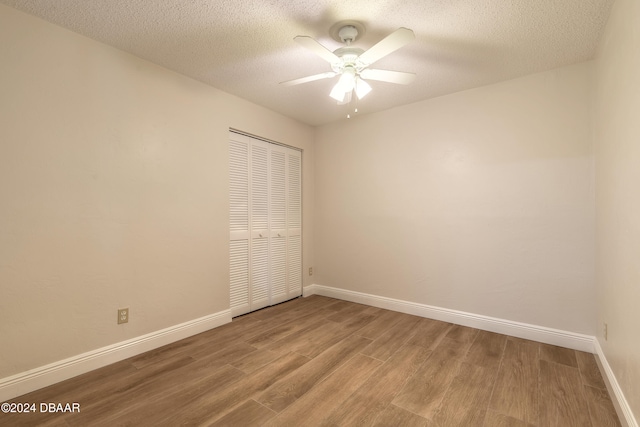 unfurnished bedroom with ceiling fan, a closet, wood-type flooring, and a textured ceiling