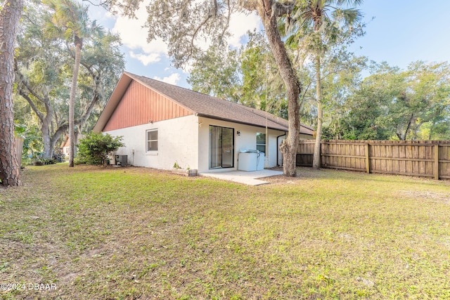 rear view of house with a lawn and cooling unit