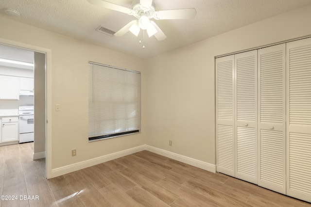 unfurnished bedroom featuring ceiling fan, light hardwood / wood-style floors, a textured ceiling, and a closet