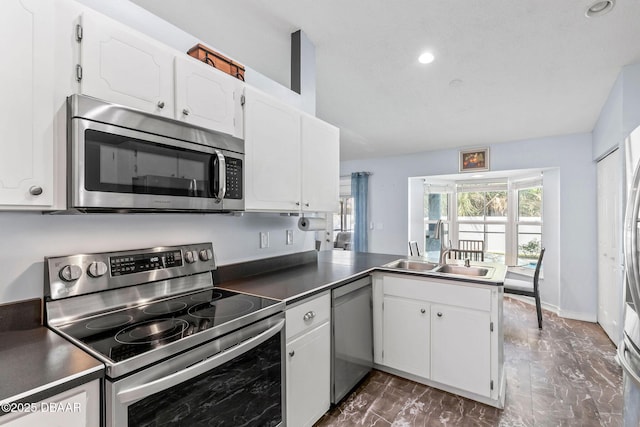 kitchen with recessed lighting, a peninsula, white cabinets, stainless steel appliances, and a sink